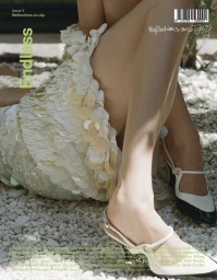 Close-up of a model's legs wearing white and black slingback heels against a gravel and stone ground for endless magazine.