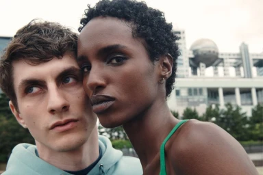 Close-up portrait of two models with a modern building and sphere structure in the blurred background for Aman Essentials