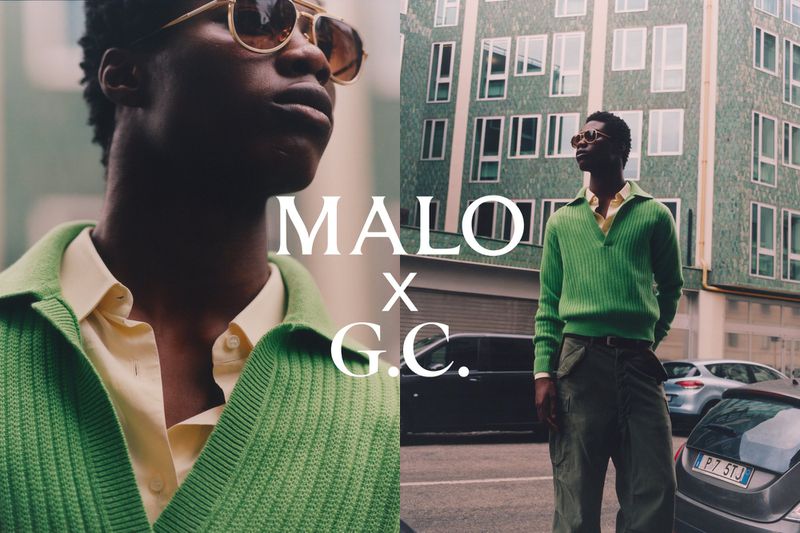 Man wearing a green ribbed polo shirt and sunglasses standing on a city street in front of a tiled green building