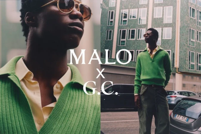 Man wearing a green ribbed polo shirt and sunglasses standing on a city street in front of a tiled green building