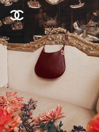 Burgundy quilted leather hobo bag hanging on an ornate vintage sofa with floral arrangements in foreground