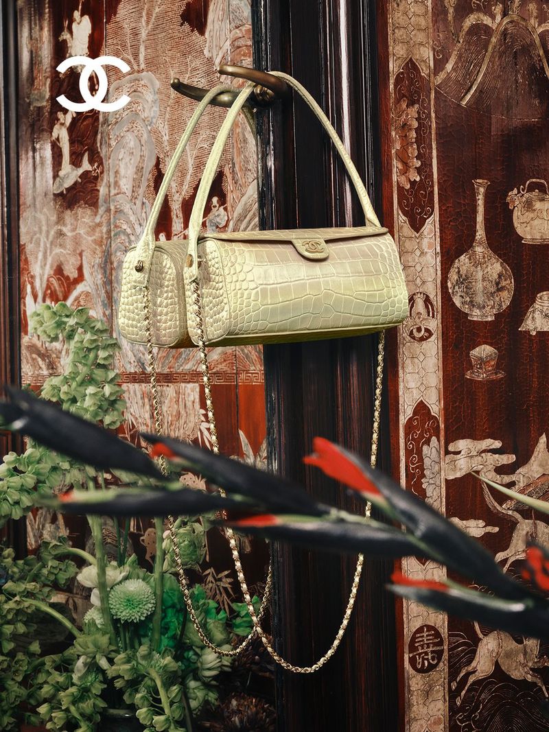 Chanel light green quilted leather handbag hanging from an ornate dark wooden door against a patterned lacquered screen.