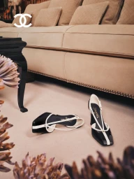 Black and white slingback heels resting on a light carpet in front of a beige sofa for Chanel Fall Winter 2026 Collection