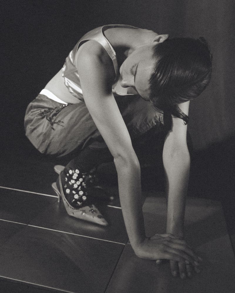 Daisy Edgar Jones crouched on tiled floor wearing a cropped top and patterned heels for Vogue Espana