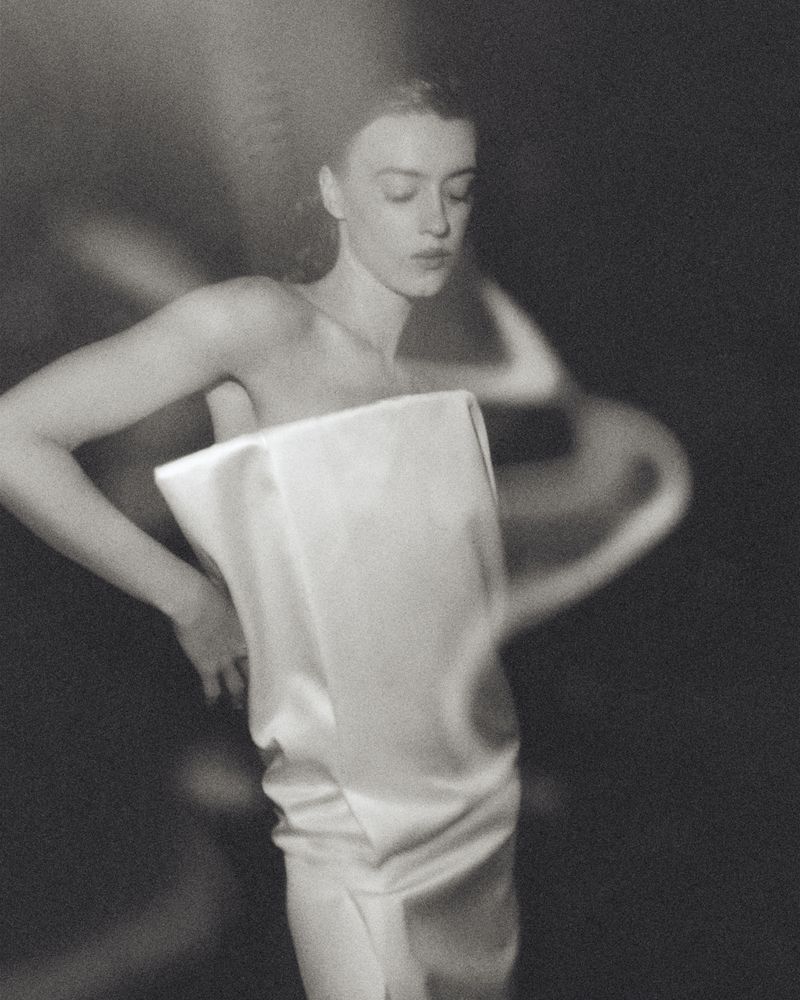 Portrait of Daisy Edgar Jones wearing a strapless white dress with motion blur effect in a monochrome aesthetic.