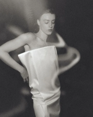 Portrait of Daisy Edgar Jones wearing a strapless white dress with motion blur effect in a monochrome aesthetic.