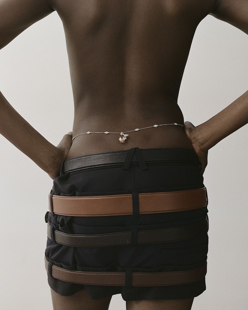 Model wearing a delicate waist chain and stacked leather belts in an editorial fashion photograph for Heroine Magazine.