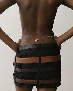 Model wearing a delicate waist chain and stacked leather belts in an editorial fashion photograph for Heroine Magazine.