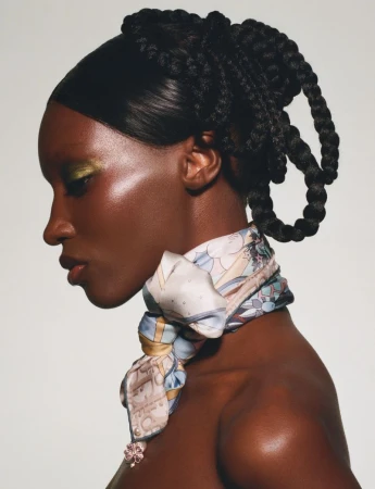 Profile portrait of a Black woman wearing a patterned silk scarf and intricate braided updo in The Dior Getaway editorial.