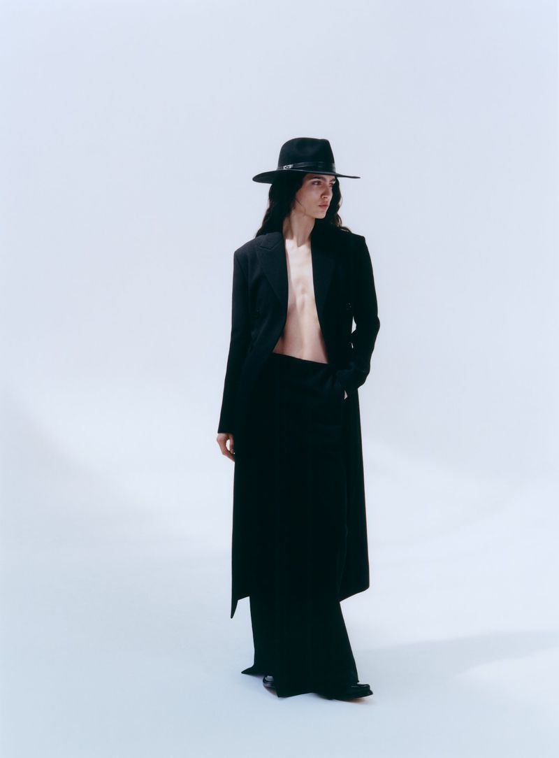 Model Sara Caballero wearing a black coat and hat against a white seamless background for Muse Magazine