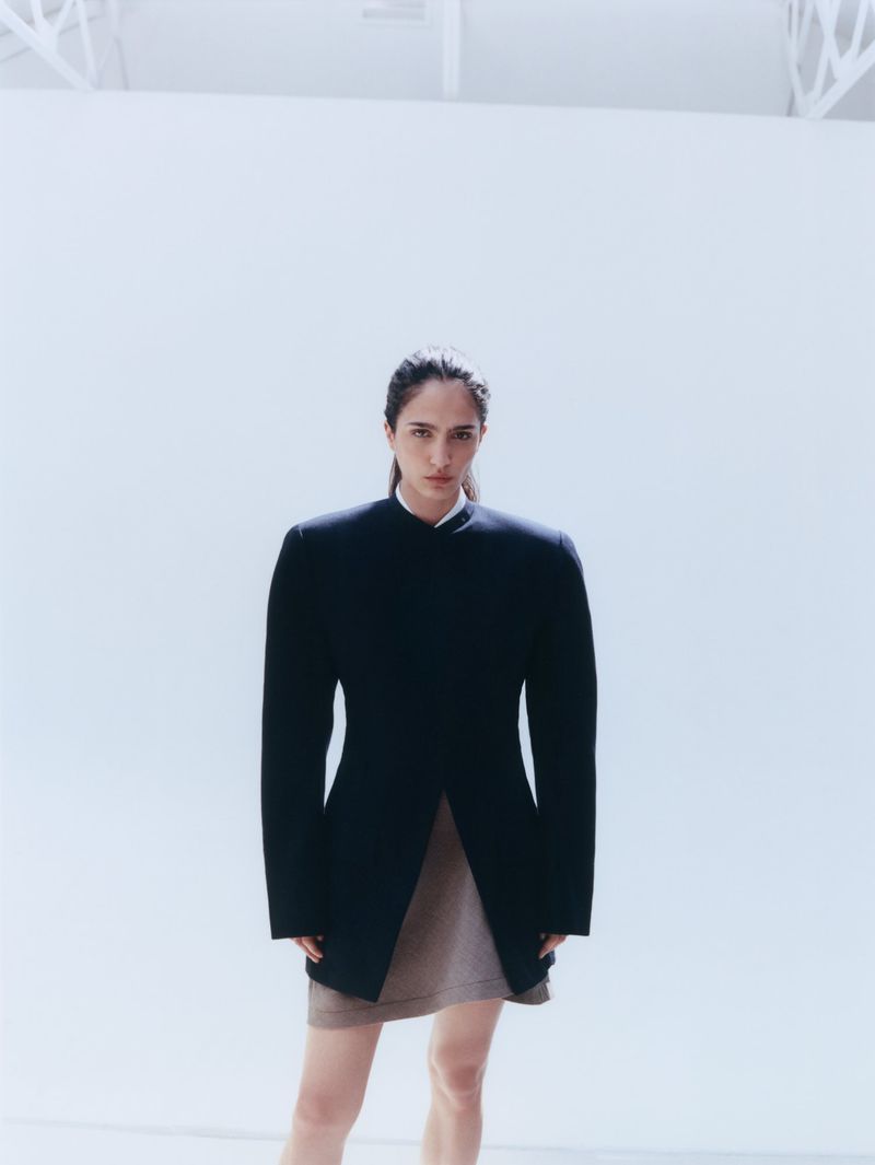 Model Sara Caballero in a dark structured jacket and skirt against a white background for Muse Magazine