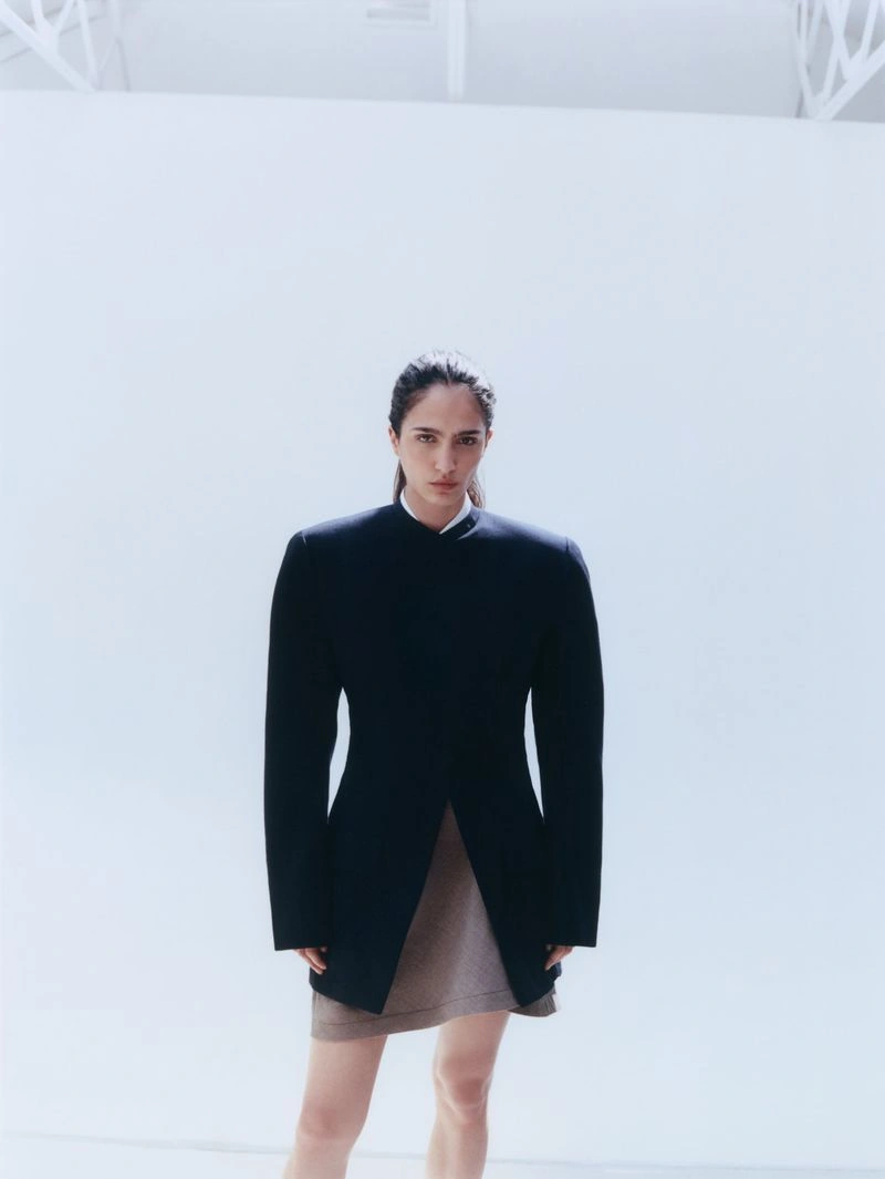 Model Sara Caballero in a dark structured jacket and skirt against a white background for Muse Magazine