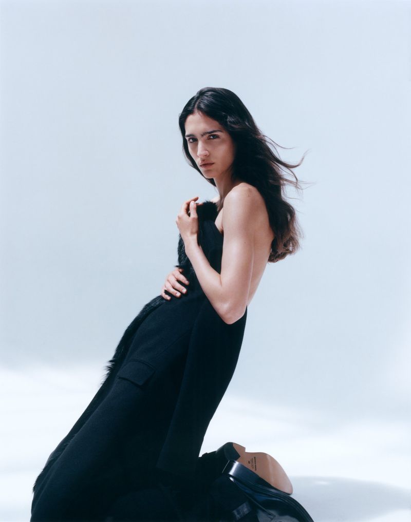 Model Sara Caballero in a black strapless dress against a white background for Muse Magazine
