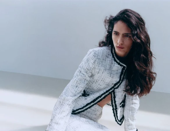 Model Sara Caballero in a white tweed jacket with black trim against a minimalist white studio background for Muse Magazine.