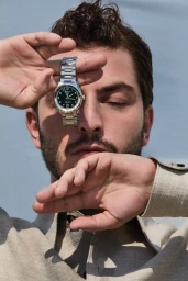 Close-up portrait of Boran Kuzum holding a silver watch in front of his eye for Citizen K Homme