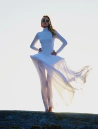 Model Emma Ellingsen wearing a white outfit and sunglasses against a bright sky background for Costume Norway.