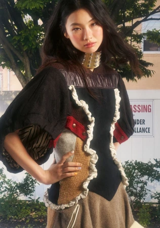 Hoyeon in a mixed-fabric structured top with a metallic choker against an outdoor street backdrop