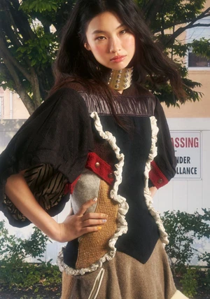 Hoyeon in a mixed-fabric structured top with a metallic choker against an outdoor street backdrop