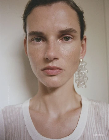 Close-up portrait of model Giedre Dukauskaite wearing a white top and clear beaded earrings for Love Want Magazine.