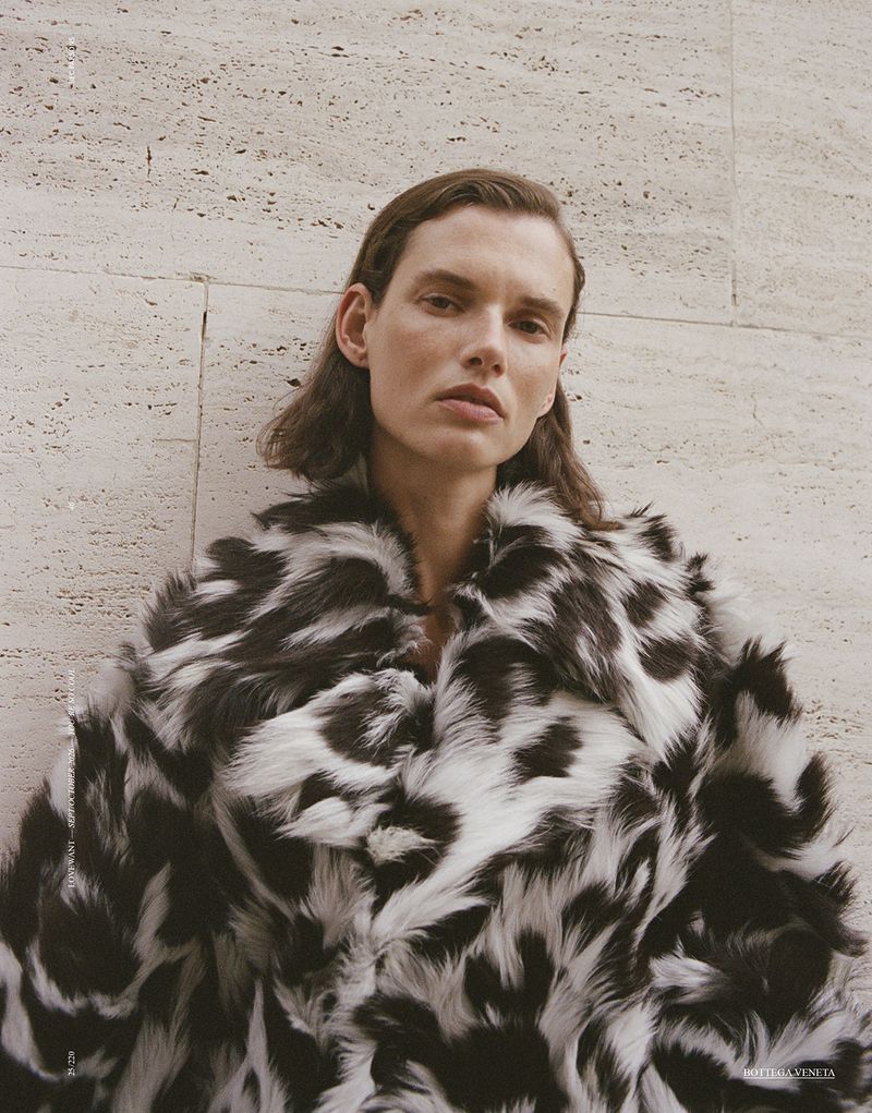 Model Giedre Dukauskaite wearing a black and white patterned faux fur coat against a textured stone wall.