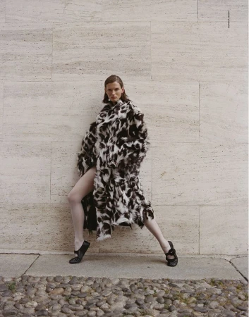 Giedre Dukauskaite wearing a black and white patterned coat against a stone wall for Love Want Magazine.