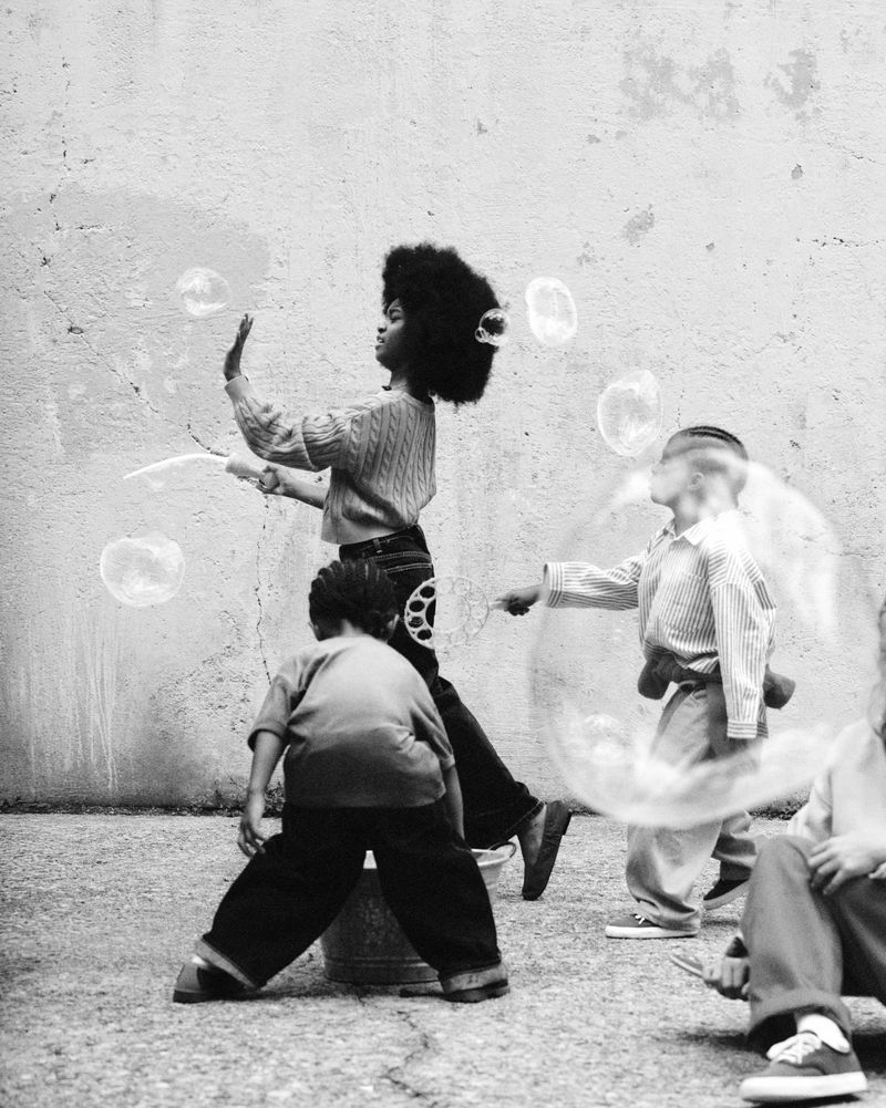 Monochrome image of children blowing soap bubbles against a textured outdoor wall for Zara X Fruit of the Loom