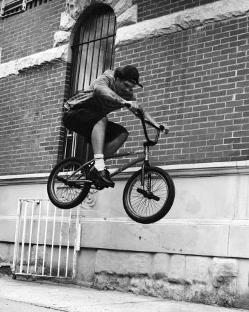 Man performing a jump on a BMX bike in front of a brick building exterior for a Zara campaign.