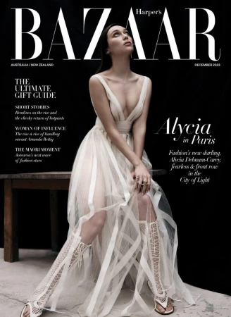 Alycia Debnam Carey seated in a white tulle gown and lace-up boots against a dark background for Harper's Bazaar Australia.