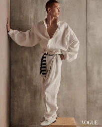 Model in white linen shirt and trousers leaning against a textured grey concrete wall for Vogue Man Philippines