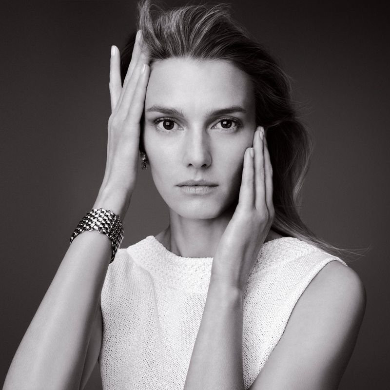 Black and white portrait of Sigrid Agren holding her face with both hands wearing a white top and a metallic bracelet for Chanel Beauty.