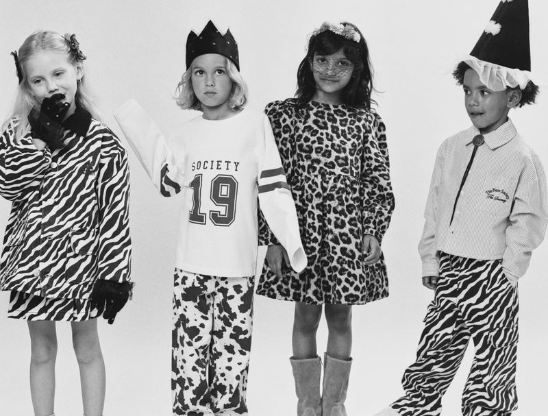 Four children posing together in animal-print and graphic clothing against a plain white studio background.