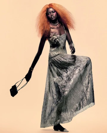 Model Caren Jepkemei with voluminous red hair wearing a grey patterned gown and holding a handbag for AURUM.