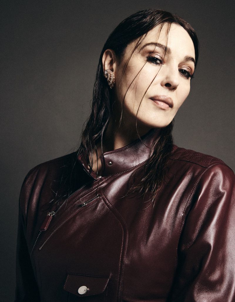 Portrait of Monica Bellucci wearing a dark leather jacket against a neutral grey studio background
