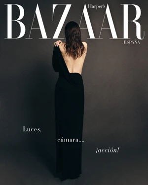 Monica Bellucci photographed from behind wearing a black evening gown against a dark grey seamless studio backdrop