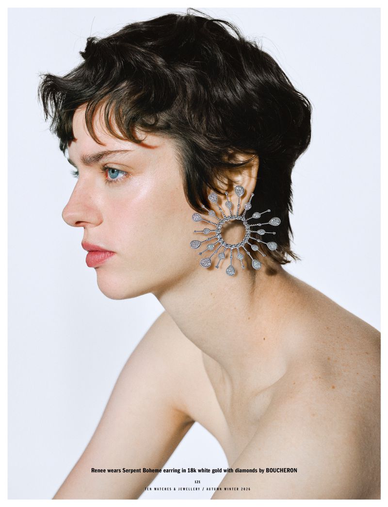 Profile portrait of a woman wearing a large jeweled sunburst earring against a white background