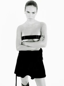 Monochrome portrait of a woman with folded arms wearing a dark bandeau top and skirt against white