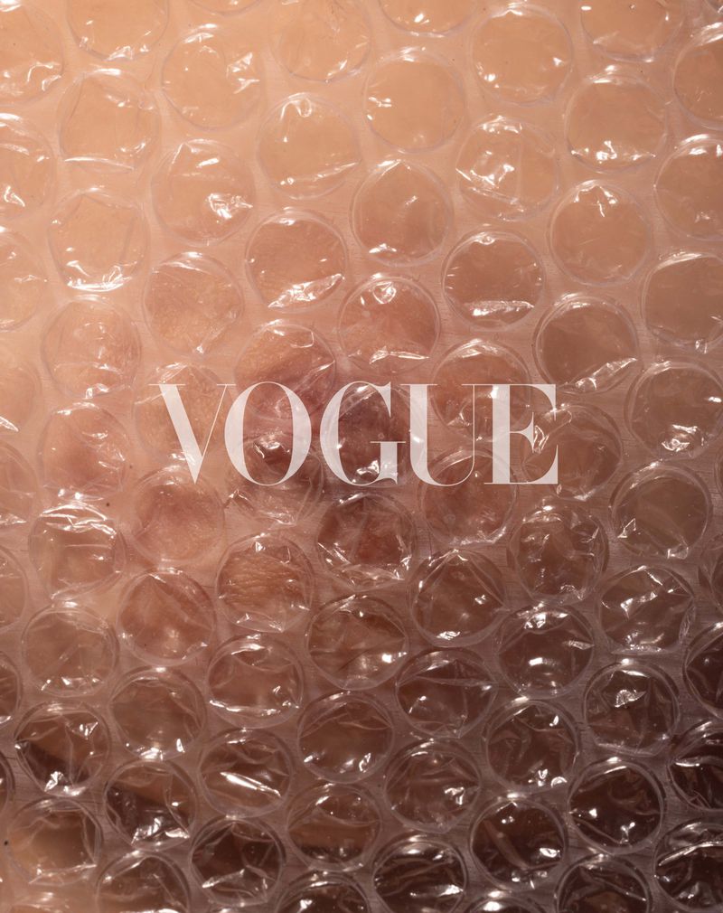 Close-up of translucent plastic bubble wrap texture with skin visible underneath and Vogue masthead