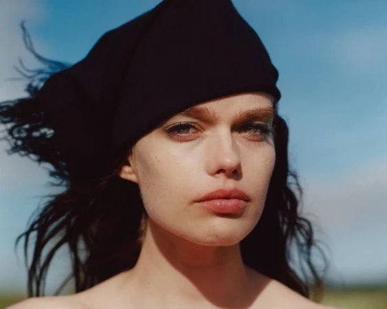 Close-up portrait of a woman wearing a black headscarf against a clear blue sky background.