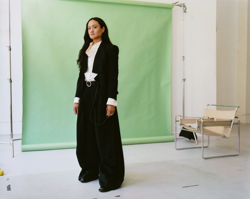 Autumn Durald Arkapaw standing in a black suit in front of a green backdrop for The Gentlewoman
