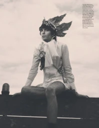 Model wearing a white shirt and leaf crown seated against an overcast sky for W Magazine editorial
