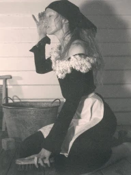 Model Raquel Zimmermann in a black top with white ruffles kneeling next to a wash tub for W Magazine, photographed by David Sims