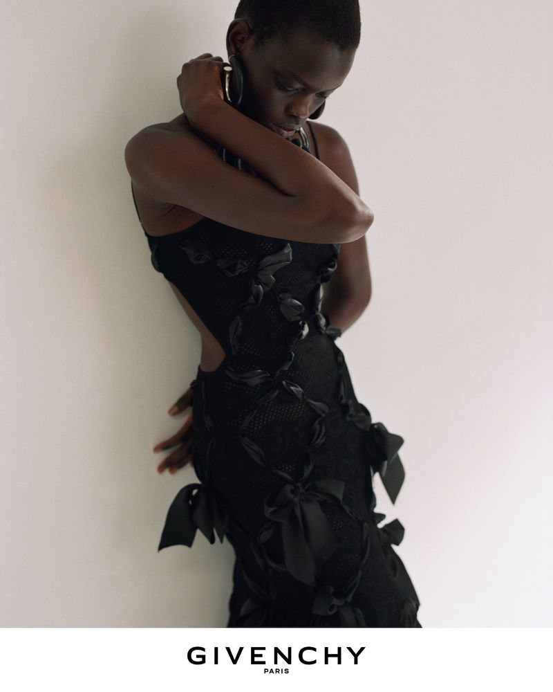 Model in a black textured dress with bow accents posing against a plain wall for Givenchy Winter 2026
