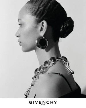 Profile portrait of a model wearing large silver statement earrings and a chunky link necklace for the Givenchy Winter 2026 campaign.