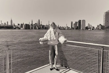 Model Tinka Carleton-Smith posing on a waterfront railing against a city skyline for Quiet Motion Issue 8