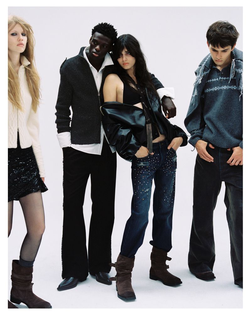 Four fashion models posing together against a plain white studio backdrop wearing contemporary streetwear.