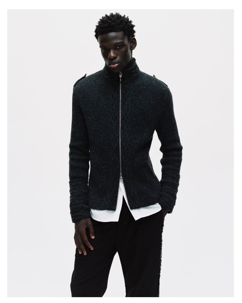 Model in dark zip-up cardigan and white shirt against a neutral white background