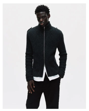 Model in dark zip-up cardigan and white shirt against a neutral white background