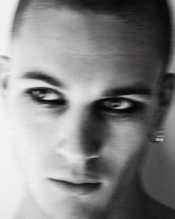 Close-up black and white portrait of a man with dark eye makeup and a motion blur effect