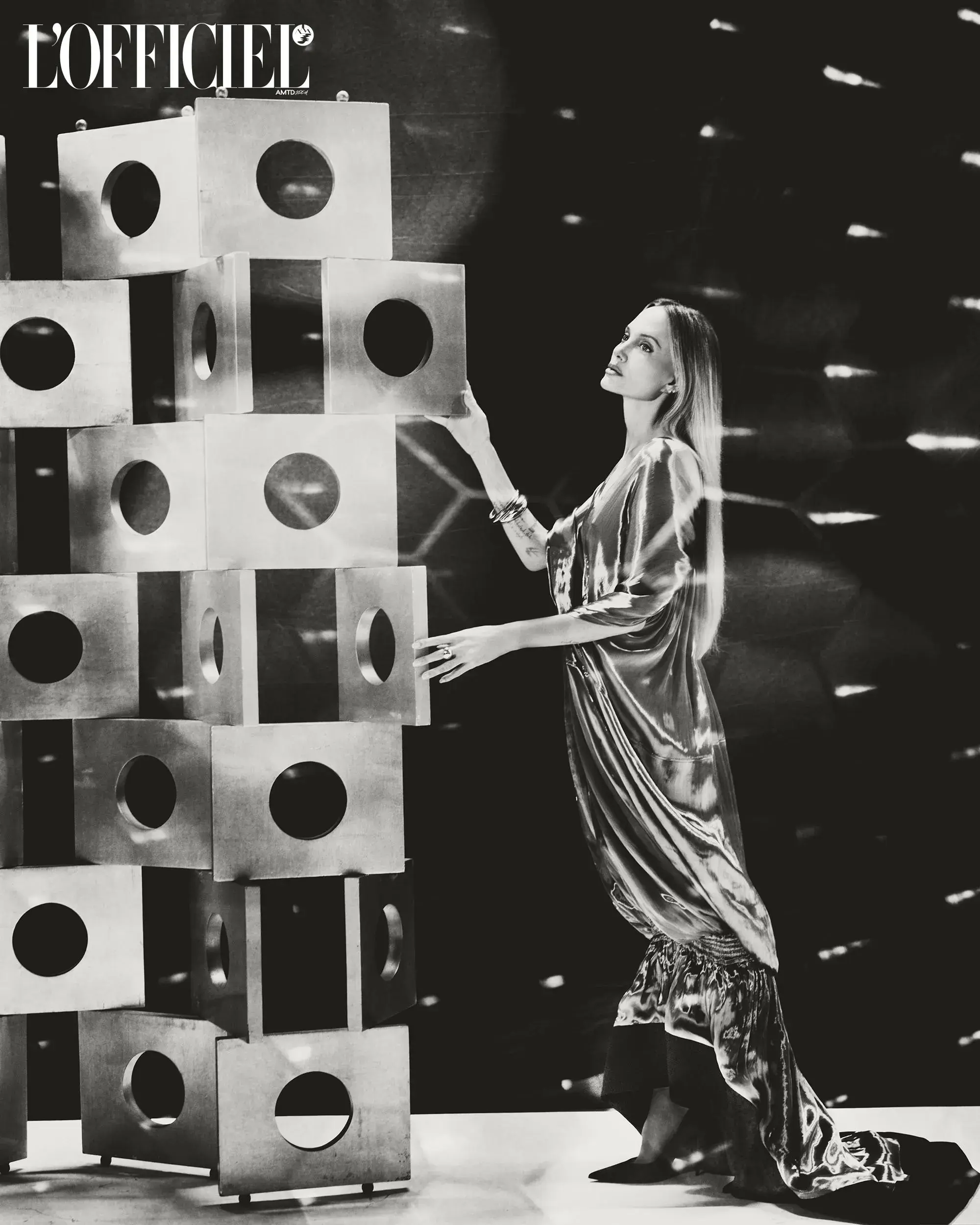 Angelina Jolie touching a tall metallic sculptural tower of stacked cubes for an L'Officiel Italia editorial feature