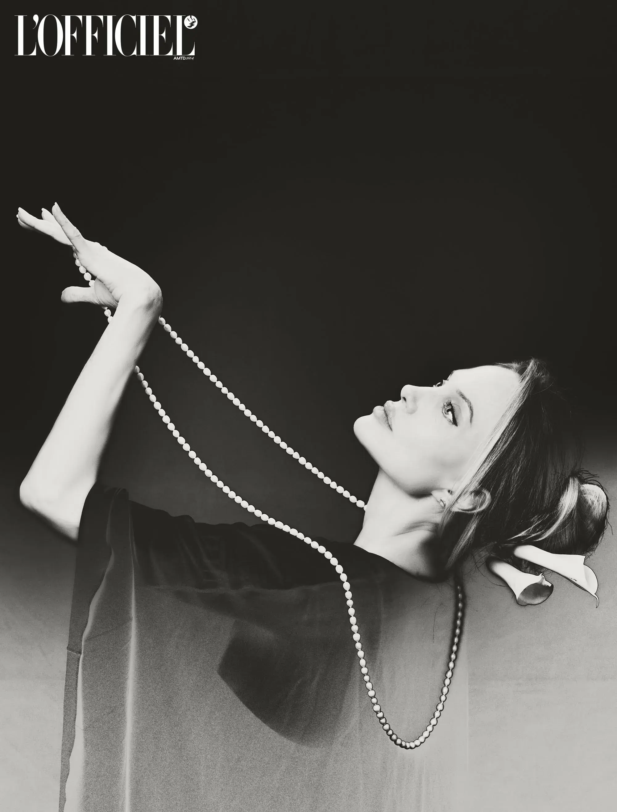 Black and white portrait of Angelina Jolie holding a pearl necklace for L'Officiel Italia